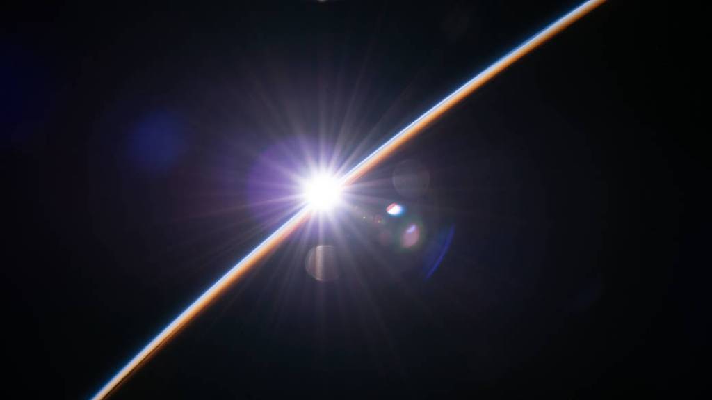The first rays of an orbital sunrise illuminate Earth’s atmosphere