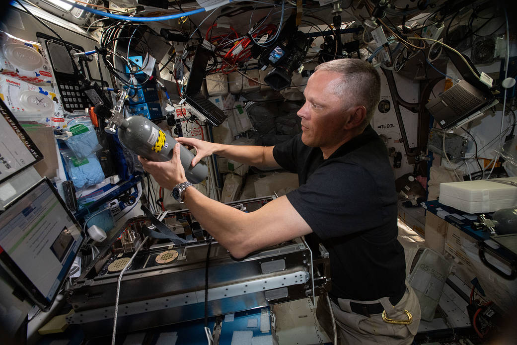 Astronaut Bob Hines replaces a carbon dioxide bottle