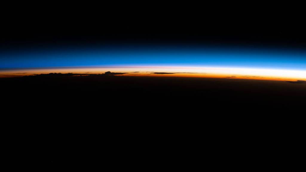 An orbital sunrise illuminate’s Earth’s atmosphere silhouetting clouds