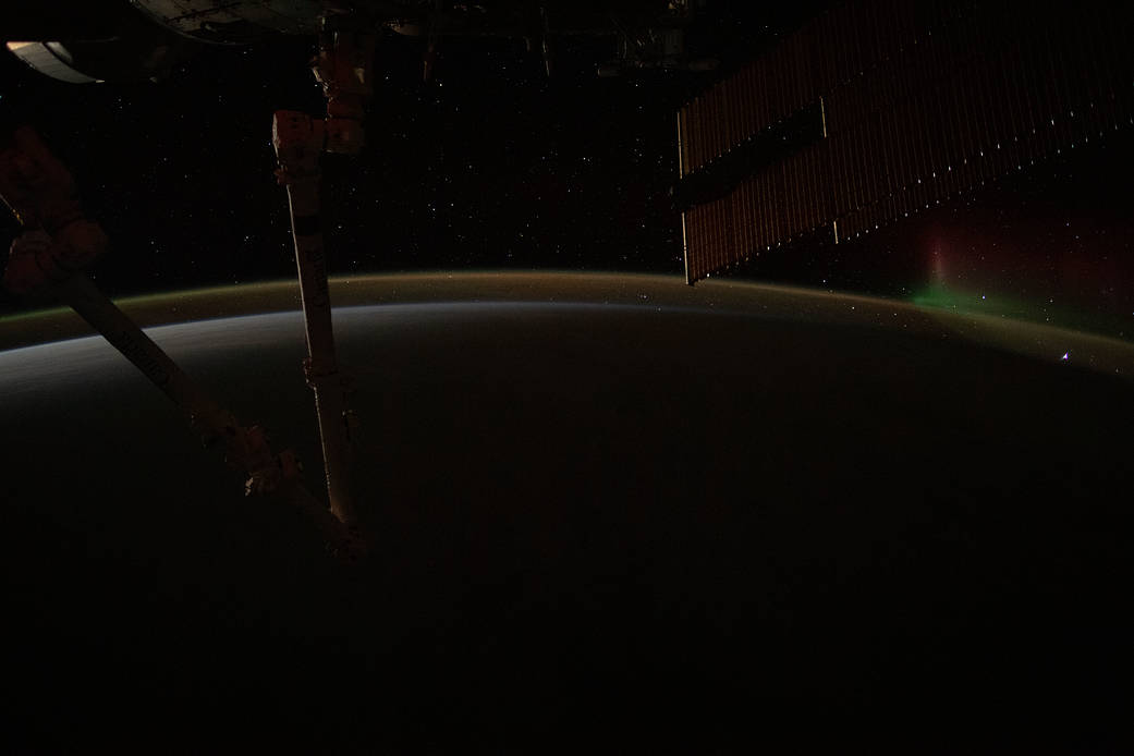 A wispy aurora fades away above Earth's atmospheric glow
