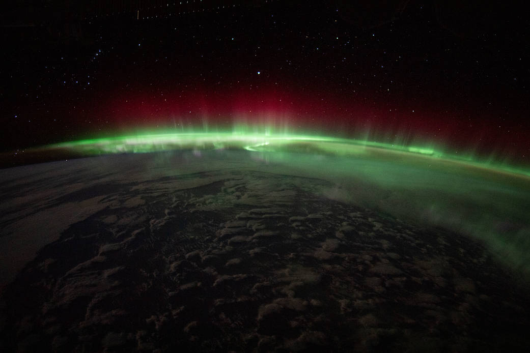 An aurora crowns the Earth beneath a starry sky
