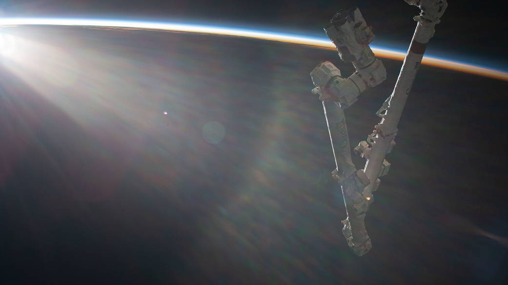 An orbital sunrise begins illuminating Earth's atmosphere