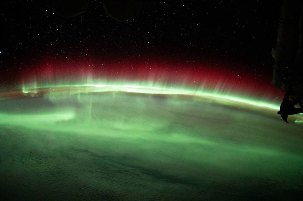 A brilliant aurora streams above Earth’s horizon