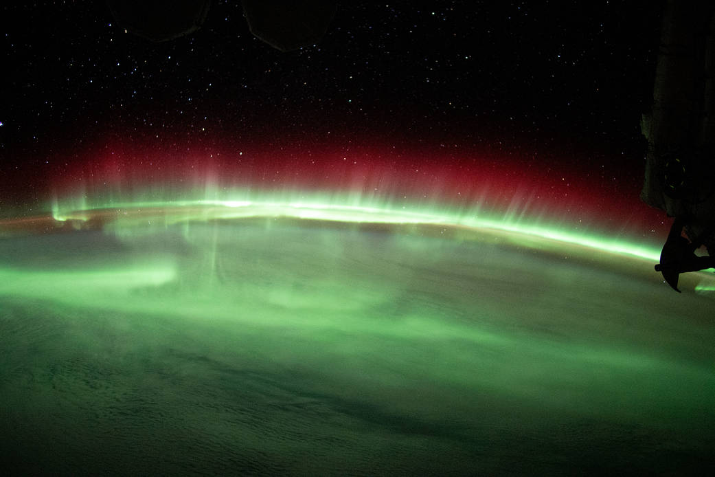 A brilliant aurora streams above Earth's horizon