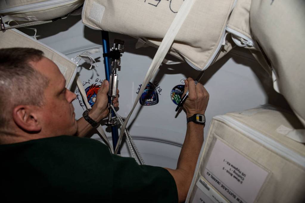 Astronaut Bob Hines signs his name on the Harmony module