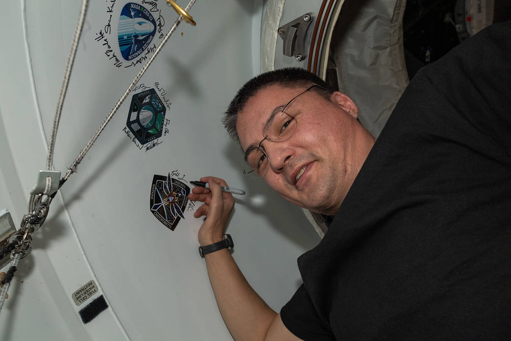 Astronaut Kjell Lindgren signs his name around the Crew-4 sticker