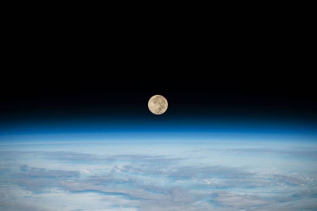 The Full Moon is pictured setting below Earth’s horizon
