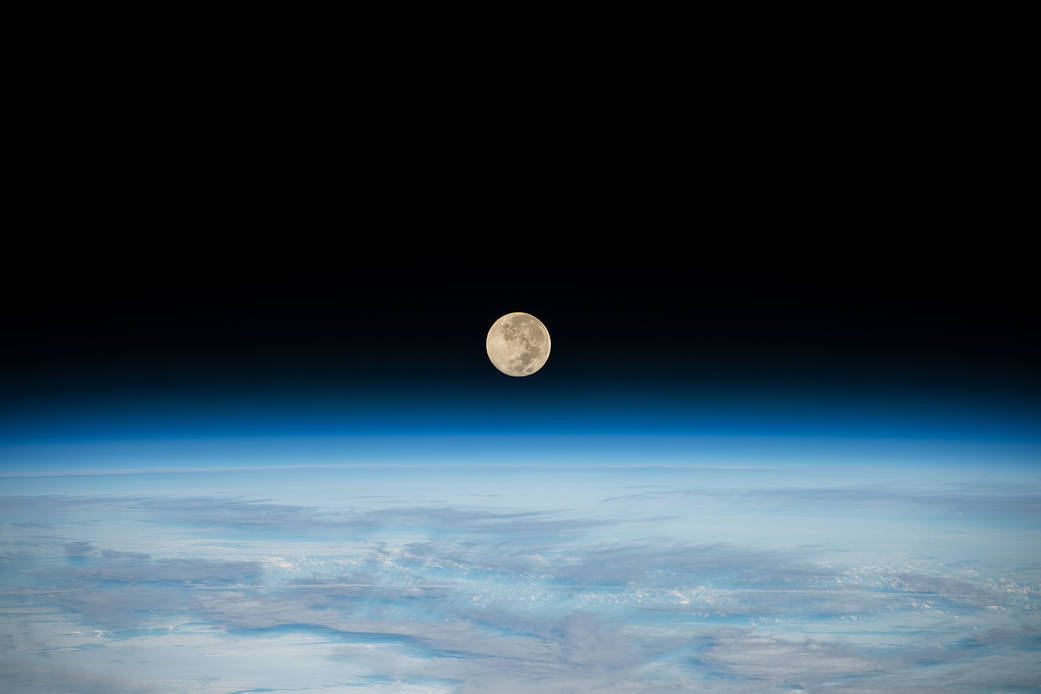 The Full Moon is pictured setting below Earth's horizon