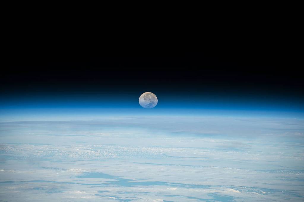 The Full Moon is pictured setting below Earth’s horizon