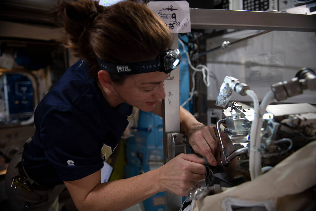 Astronaut Nicole Mann replaces life support gear on a spacesuit
