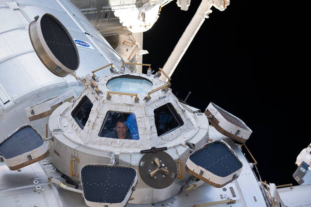 NASA astronaut Josh Cassada peers through a window in the cupola