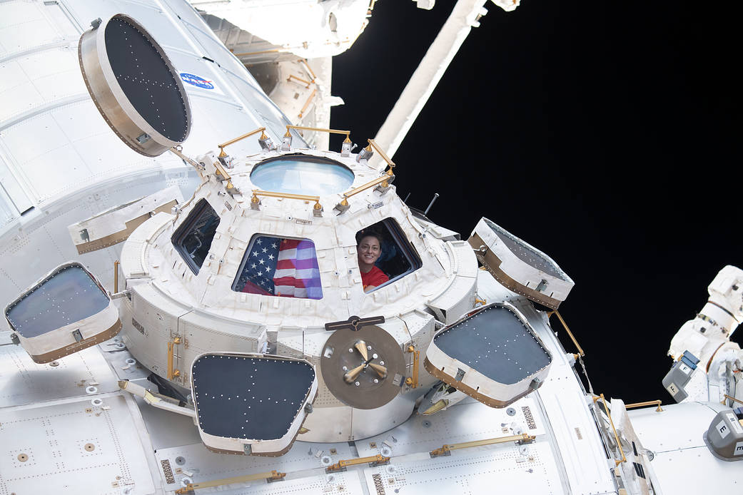 NASA astronaut and Expedition 68 Flight Engineer Nicole Mann peers through one of the seven windows in the cupola, the International Space Station's "window to the world." Mann displays the U.S. flag inside the cupola in the window next to her.