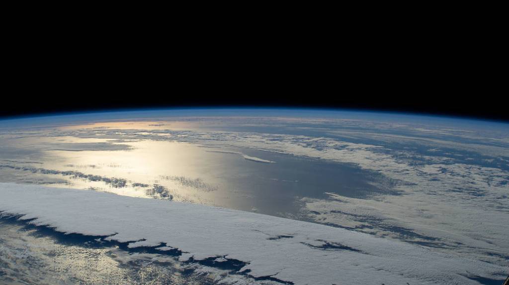 The sun’s glint beams off a partly cloudy Pacific Ocean