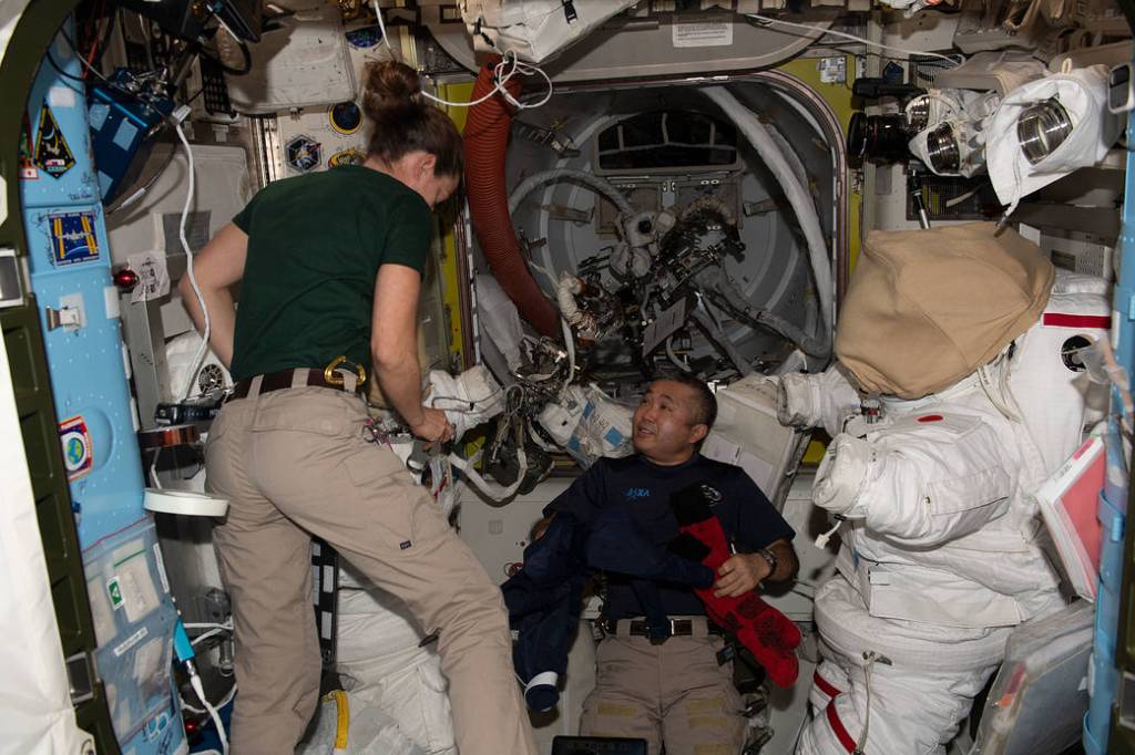 Astronauts Nicole Mann and Koichi Wakata work on spacesuits