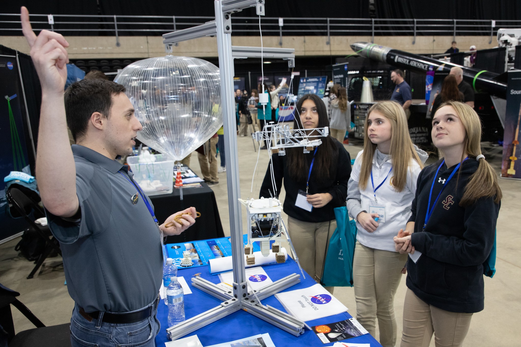 Evan Youngberg points up in the air while explaining scientific balloons to three students.