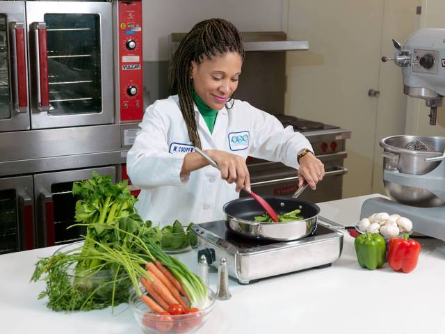 A food scientist with the JSC Space Food Systems Laboratory cooks with fresh vegetables.