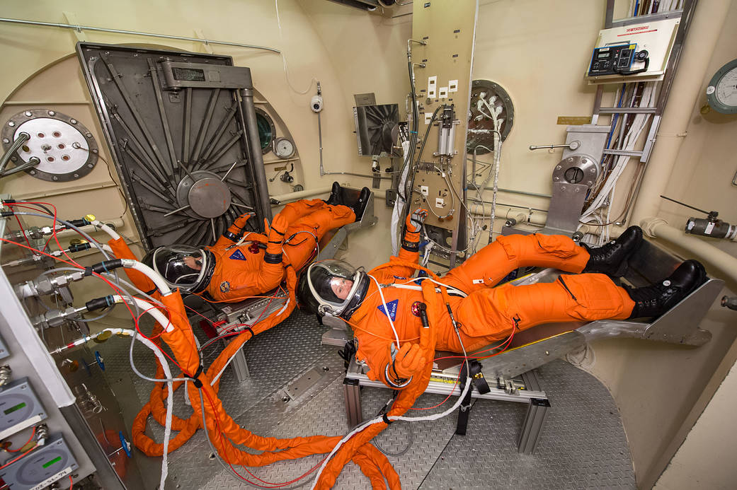Two individuals in orange astronuat suits.