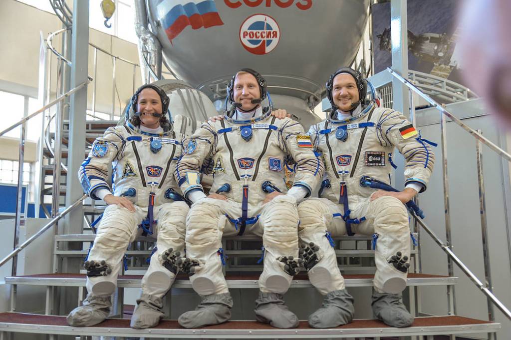 Expedition 56 crew members in front of a Soyuz simulator