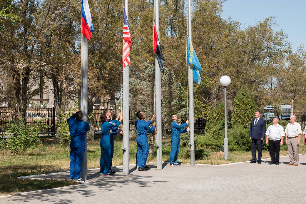 The prime and backup crewmembers for the next launch to the space station raise the flags 