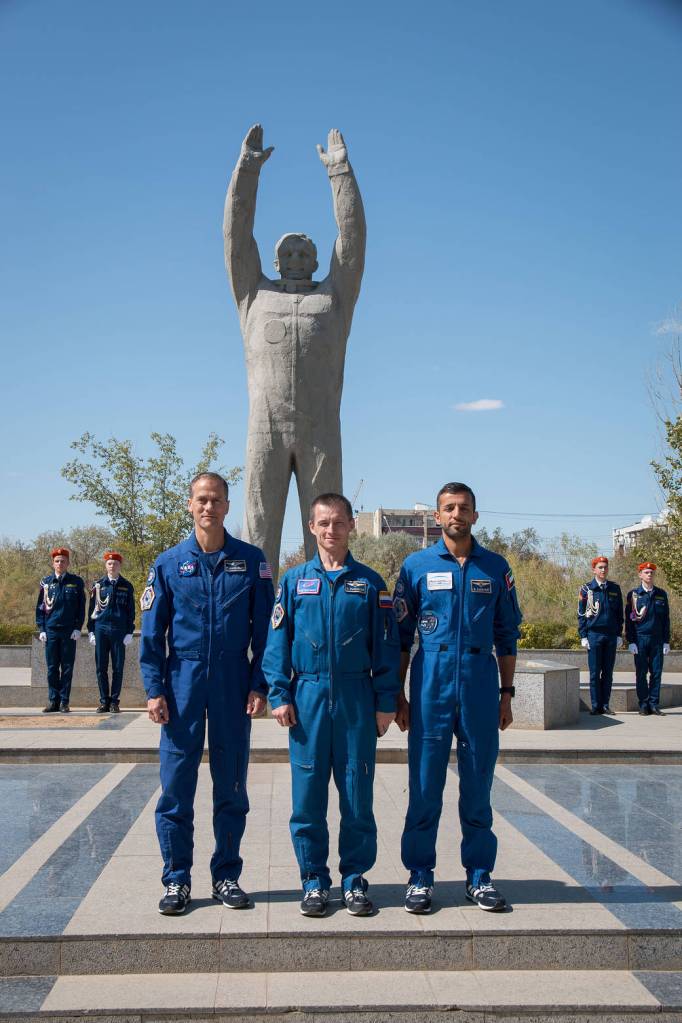 The backup crewmembers for the next launch to the space station in front of a statue of Yuri Gagarin