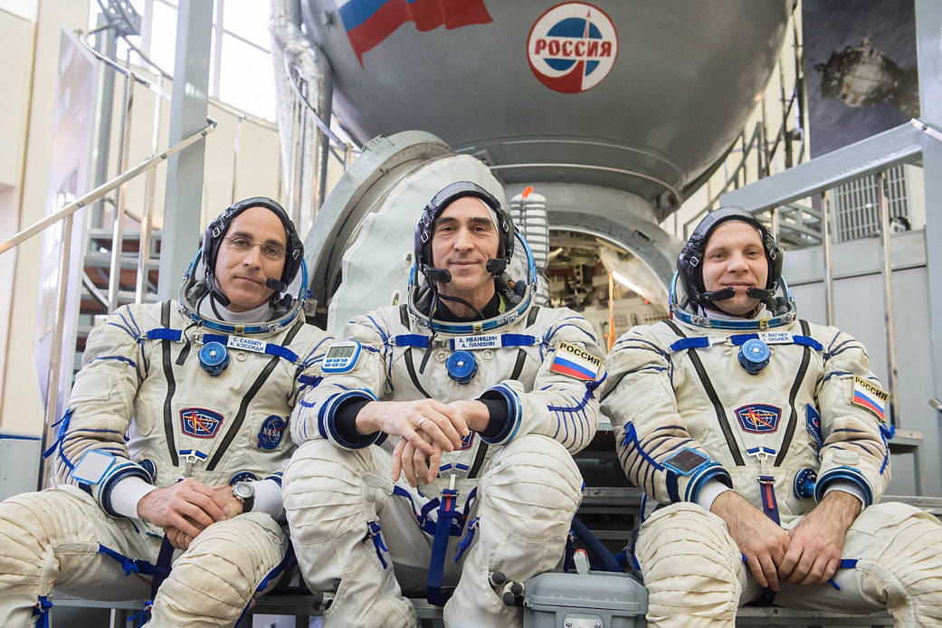 Expedition 63 crewmembers pose in front of a Soyuz trainer