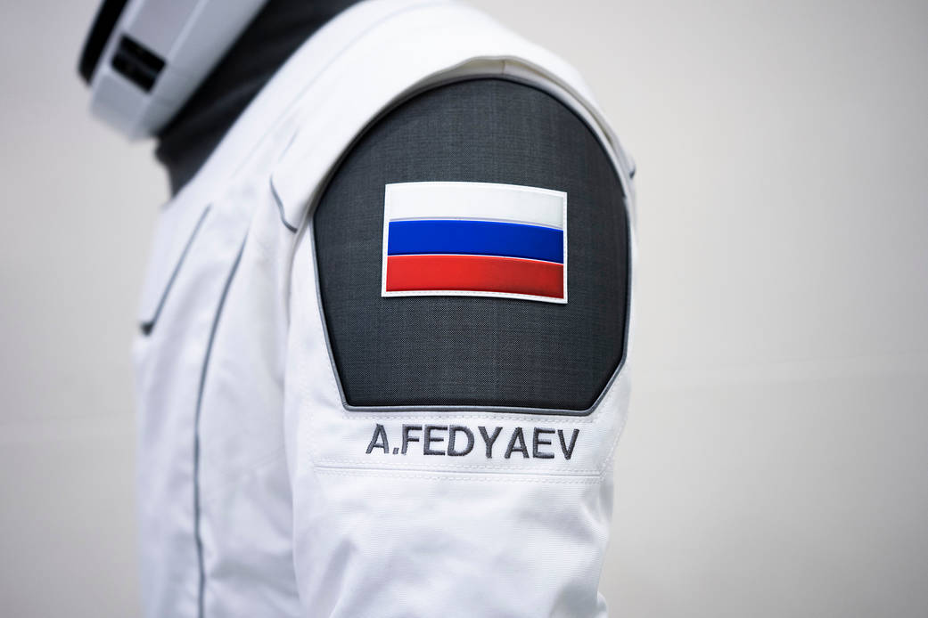 A SpaceX launch and entry suit bears a Russian flag