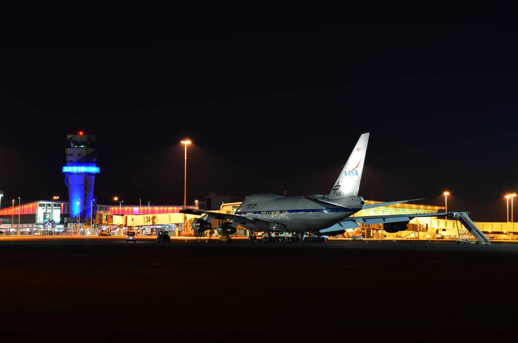 Night shot of SOFIA, with terminals and control tower of Christchurch International Airport in the background.