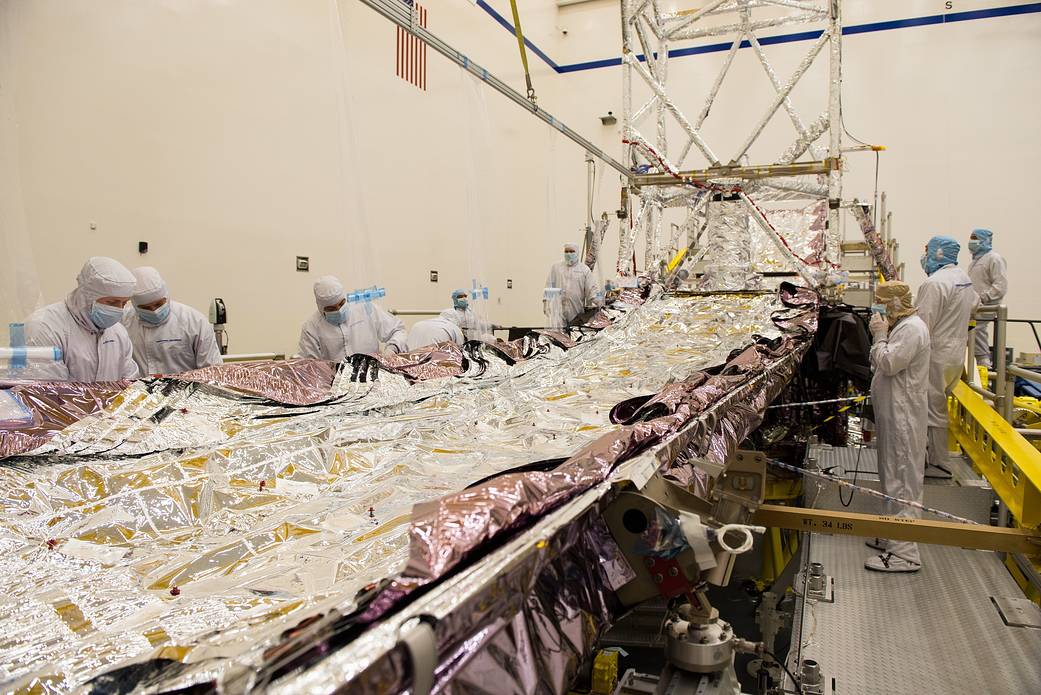 Technicians lay the sunshield flat for inspection.