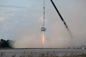 At NASA’s Kennedy Space Center in Florida, smoke fills the air as the Project Morpheus prototype lander’s engine fires during a tether test at the north end of the Shuttle Landing Facility.
