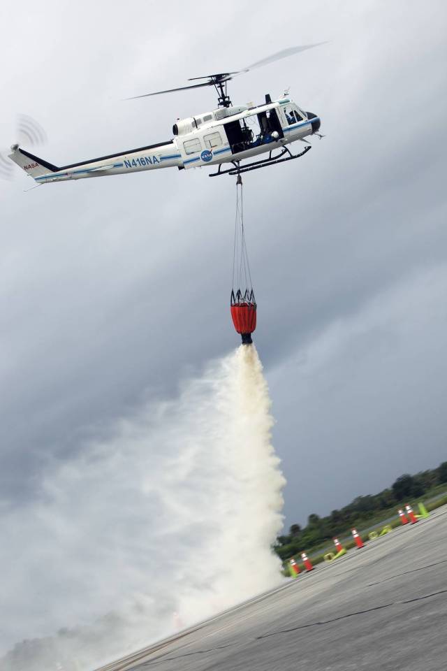 At NASA's Kennedy Space Center in Florida, a three-person helicopter crew recently practiced using a Bambi Bucket to pick up water from a nearby waterway and dropping it on simulated targets at the center’s Shuttle Landing Facility.