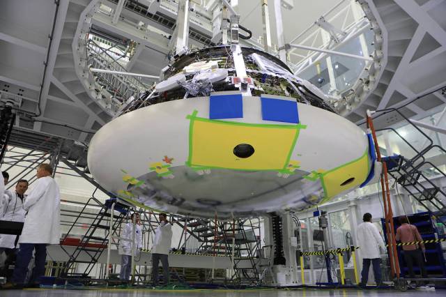 Lockheed Martin engineers and technicians are installing the heat shield to the Orion crew module July 25, 2018, inside the Neil Armstrong Operations and Checkout Building high bay at NASA's Kennedy Space Center in Florida. 