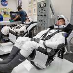 NASA astronauts Doug Hurley, foreground, and Bob Behnken don SpaceX spacesuits in the Astronaut Crew Quarters at Kennedy Space Center in Florida on Jan. 17, 2020.