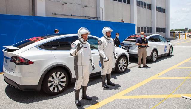 On May 23, 2020, NASA astronauts Robert Behnken (right) and Douglas Hurley pose for a photo as they prepare to take a ride in a Tesla.