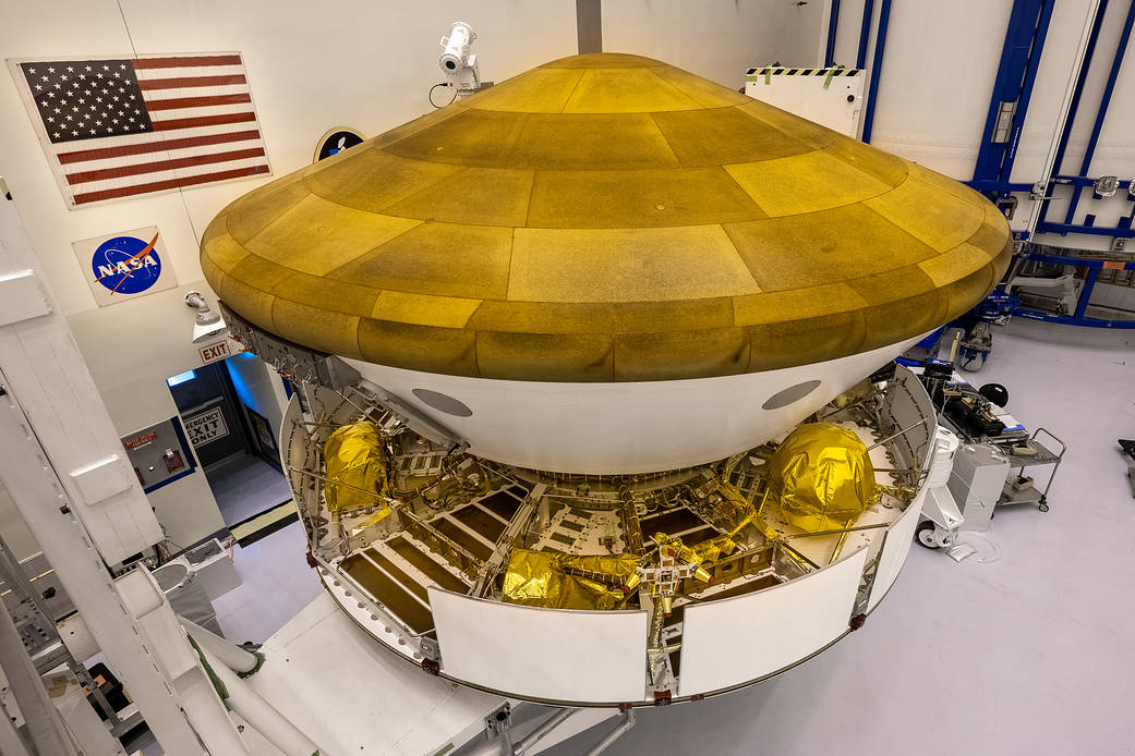 Inside the Payload Hazardous Servicing Facility at NASA’s Kennedy Space Center in Florida, the Backshell-Powered Descent Vehicle, in view, and Entry Vehicle assemblies are being attached to the Mars Perseverance rover on May 29, 2020.