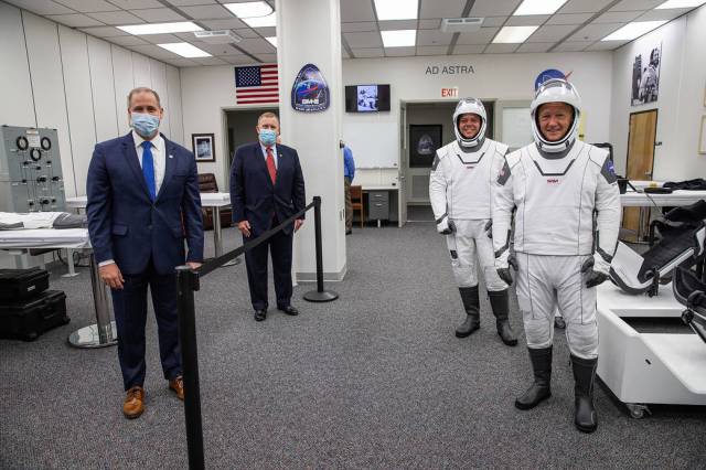 Behind the rope, NASA Administrator Jim Bridenstine (left) and Deputy Administrator Jim Morhard pause for a photo with NASA astronauts Robert Behnken (left) and Douglas Hurley.