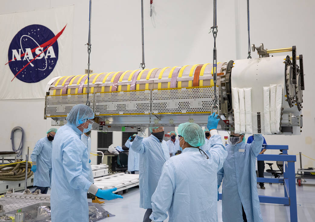NASA and Boeing workers lift solar arrays that will fly to the International Space Station into flight support equipment.
