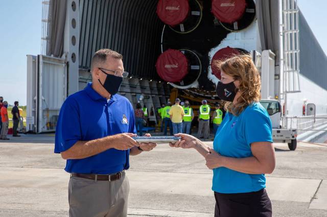 Space Launch System Stages Manager Julie Bassler, right, celebrates the arrival of the SLS core stage by symbolically “passing the baton” to Exploration Ground Systems’ Senior Vehicle Operations Manager Cliff Lanham.