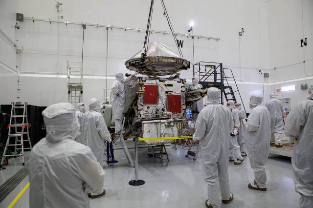 Workers assist as a crane lowers the high gain antenna for installation on NASA’s Lucy spacecraft inside the Astrotech Space Operations Facility in Titusville, Florida.