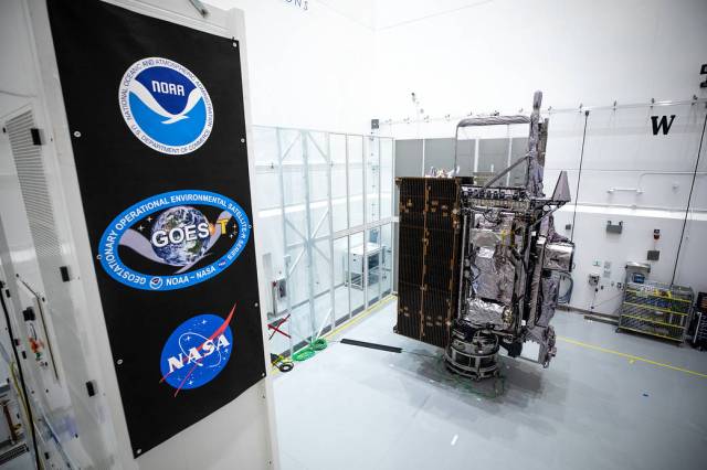 NOAA’s Geostationary Operational Environmental Satellite-T (GOES-T) is in view alongside its banner inside the Astrotech Space Operations facility in Titusville, Florida.