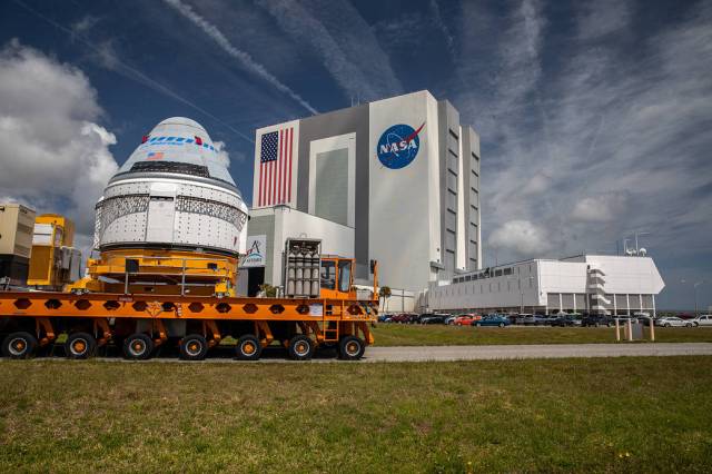 Boeing’s CST-100 Starliner spacecraft passes by the Vehicle Assembly Building at Kennedy, making its way to the Space Launch Complex-41 Vertical Integration Facility ahead of the OFT-2 launch.