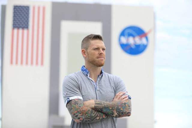 Ronnie Adams stands in front of the Vehicle Assembly Building with his arms folded in front of his chest. 