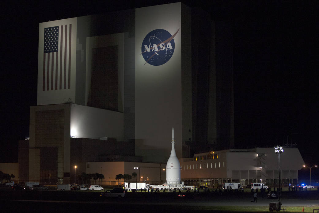 Orion crew vehicle stack rolls past the Vehicle Assembly Building at Kennedy Space Center.