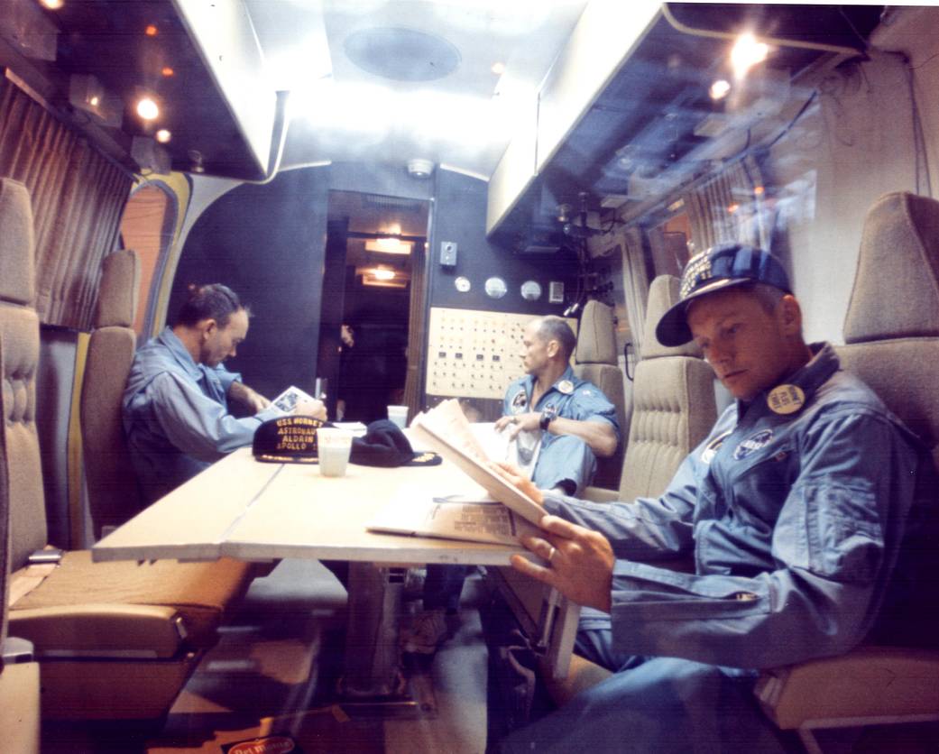 Three Apollo 11 astronauts seated at a table, relaxing inside the Mobile Quarantine Facility