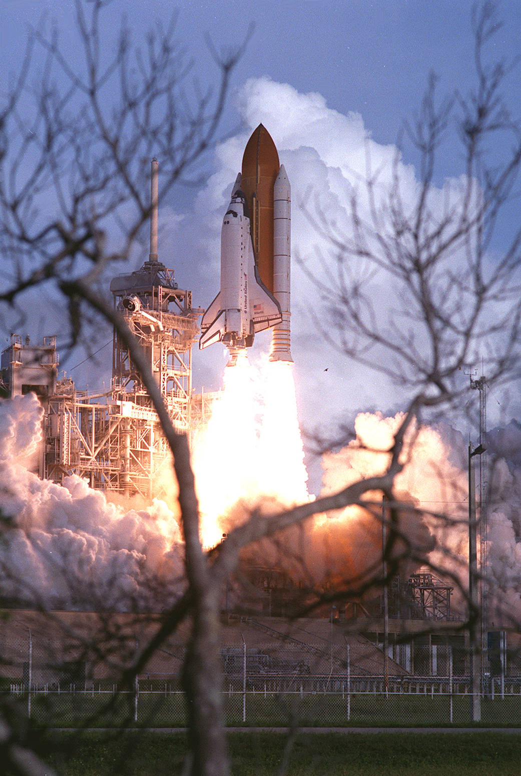 Bare branches frame the liftoff of Space Shuttle Atlantis on mission STS-106 to the International Space Station. 
