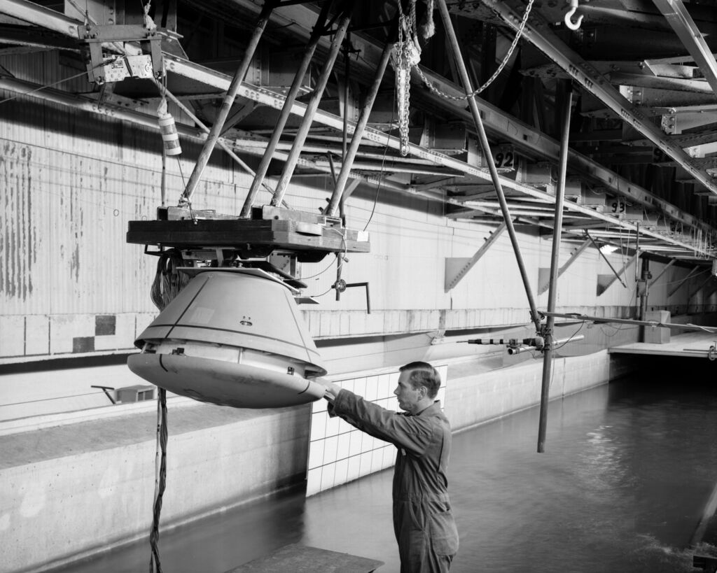 1/4th Scale Model of Apollo - Impact Structures Facility Launched from an overhead pendulum device, this Apollo spacecraft was tested in the Impact Structures Facility to determine water-landing characteristics. -- Photograph published in Winds of Change, 75th Anniversary NASA publication (page 91), by James Schultz.