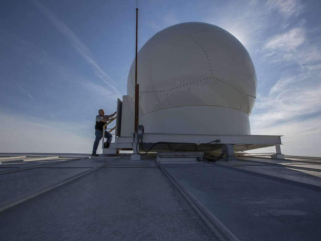 Communications Engineer Lee Joyce opens the door to a sphere containing a new antenna and tracking system, LRAS.