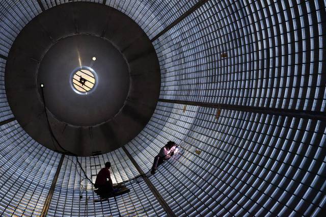 Welders inside a large liquid hydrogen tank being manufactured for NASA's Space Launch System at the Michoud Assembly Facility.