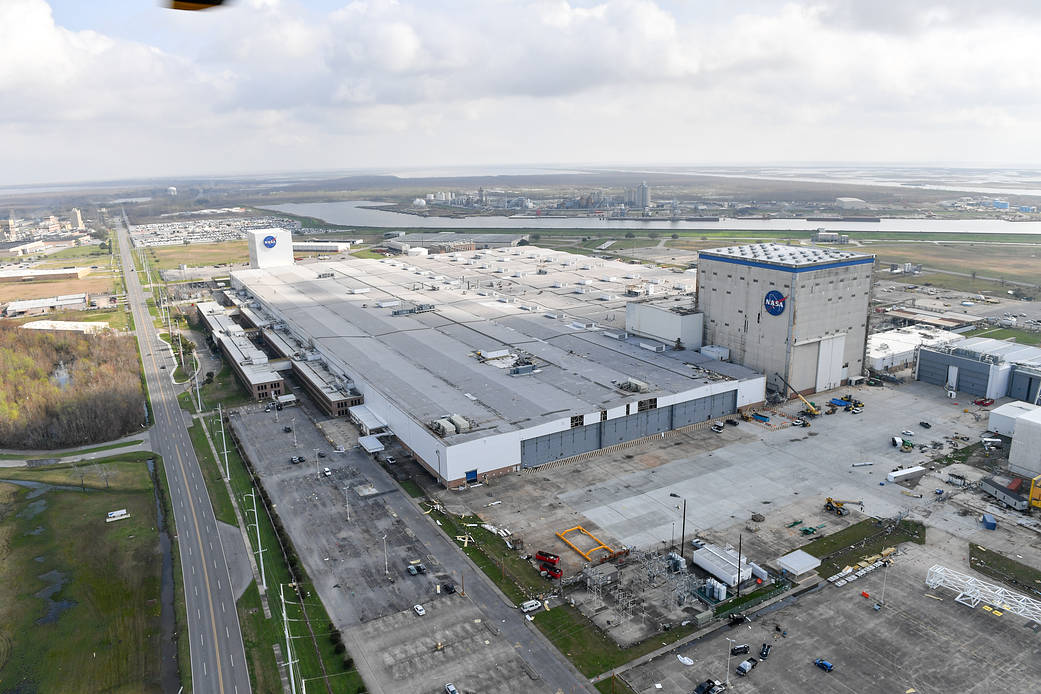 A crane being used to clear some of the debris and damage to roofs and walls at NASA's Michoud Assembly Facility