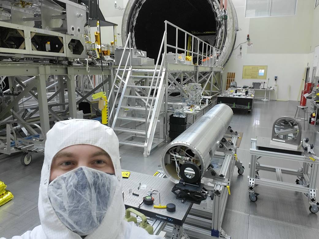 Photo of engineer in lab with sounding rocket payload in background
