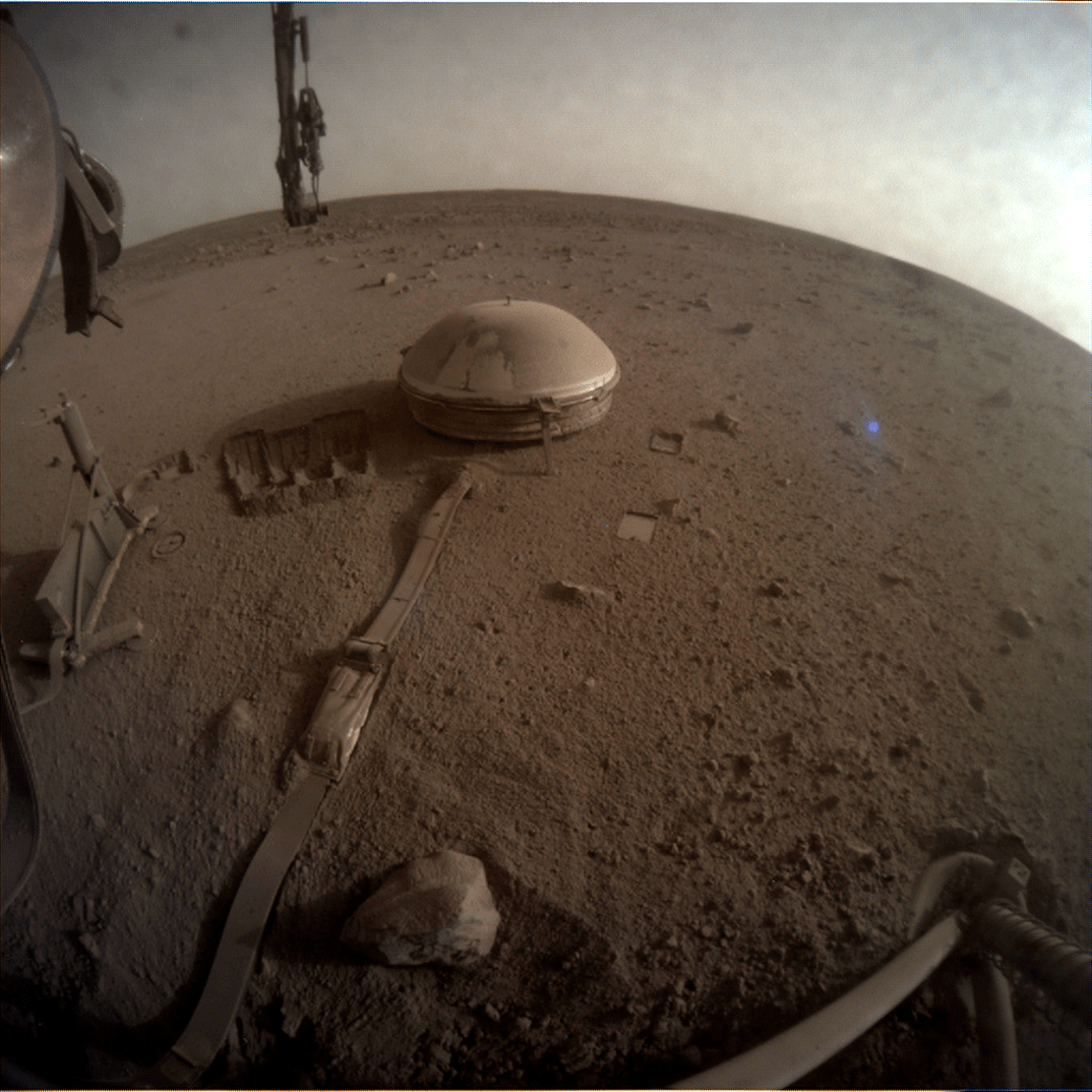 Surface of Mars in front of Mars InSight Lander, with lander leg visible in foreground and SEIS instrument deployed nearby